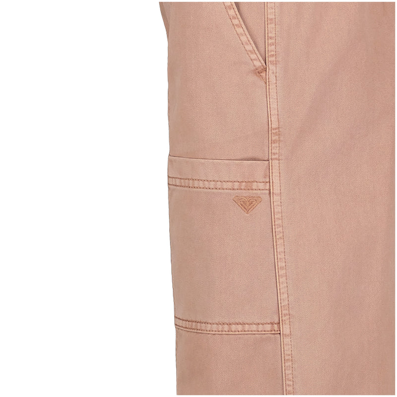 Close-up of Roxy Girls' Precious Cargo Pant in light pink cotton canvas twill, featuring detailed stitching, an embroidered heart logo near the seam and pocket, and classic cargo elements with a relaxed fit.