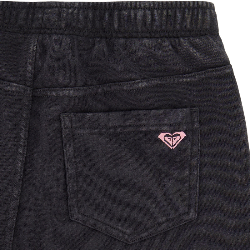 Close-up of the back pocket on Roxy Girls' Jump Start Jogger. Features an elastic waistband and a small pink embroidered heart-shaped logo above the pocket, crafted from soft cotton fleece.