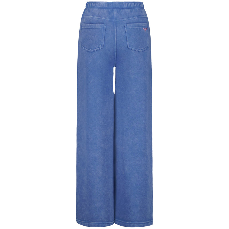 Back view of the Roxy Girls' Jump Start Jogger, wide-leg blue pants with an elastic waistband and two back pockets—one accented by a red stitched detail. Made from soft cotton-poly fleece with a lightly washed finish.