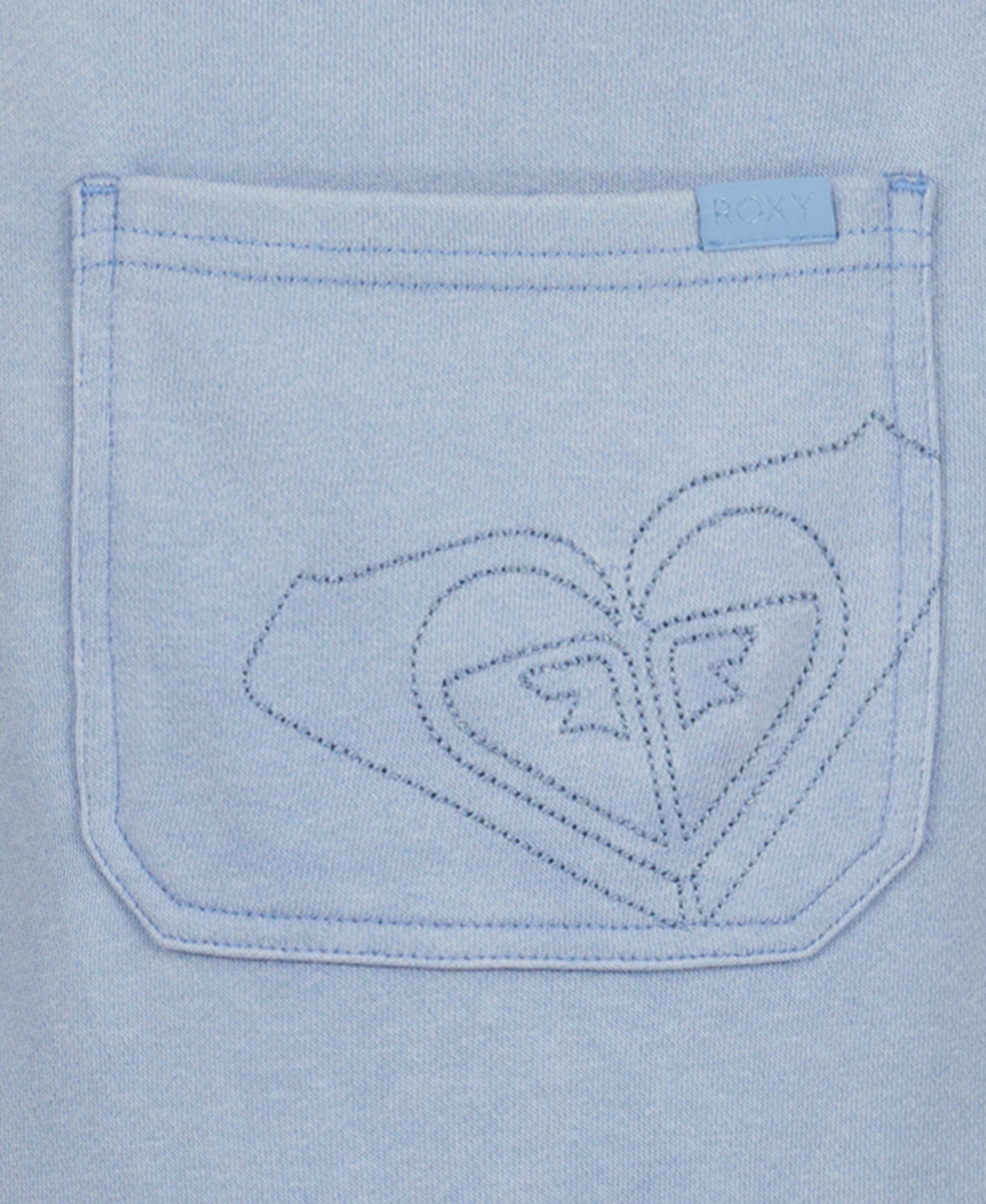 A close-up of a light blue cotton-poly French terry pocket with decorative heart-shaped stitching and a Roxy tag, perfect for pairing with the Girls' Coastline Overall by Roxy.