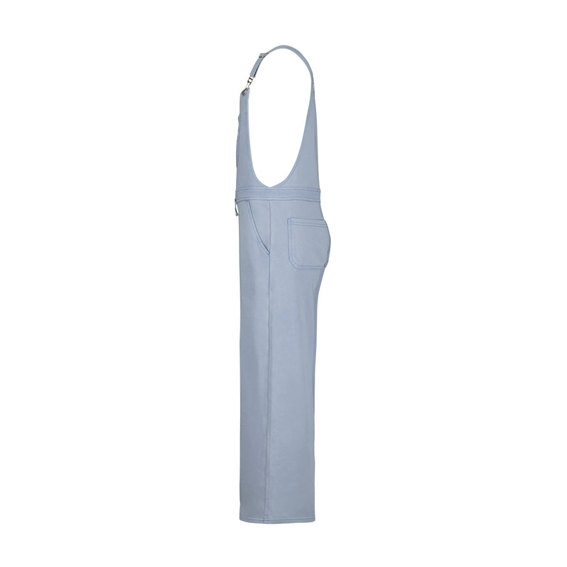 Girls' Coastline Overall by Roxy in light blue denim, shown side view with straight leg, side pocket, and adjustable metal-clip straps. Made of soft cotton-poly French terry. Set on a plain white background.