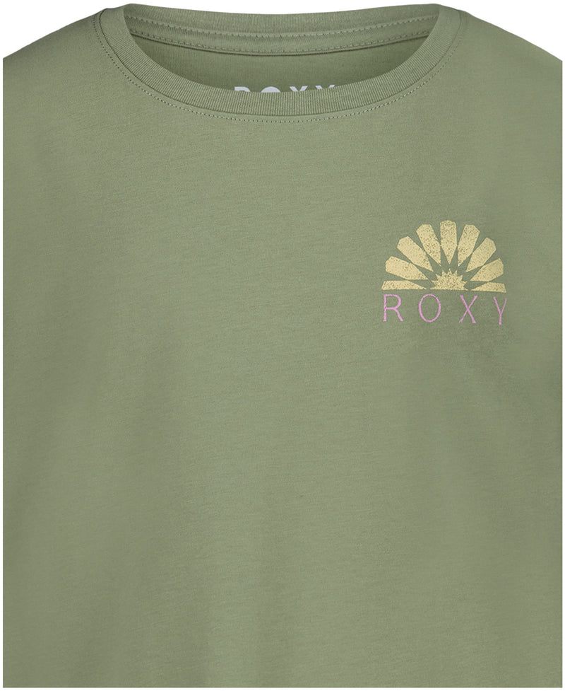 A close-up of the Roxy Girls' Sun Mosaic Tee, an oversized crew top in soft sage green cotton jersey, featuring a small pink sunburst graphic and "ROXY" on the left chest.