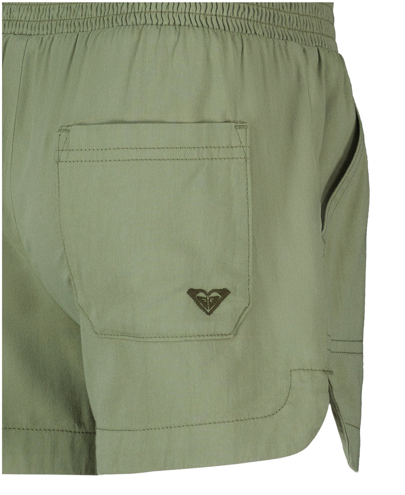 Close-up of the back and side of Roxy Girls' Soleil Short in light olive green, featuring a smocked elastic waistband, back pocket, small embroidered logo, and lightweight fabric for a casual look.