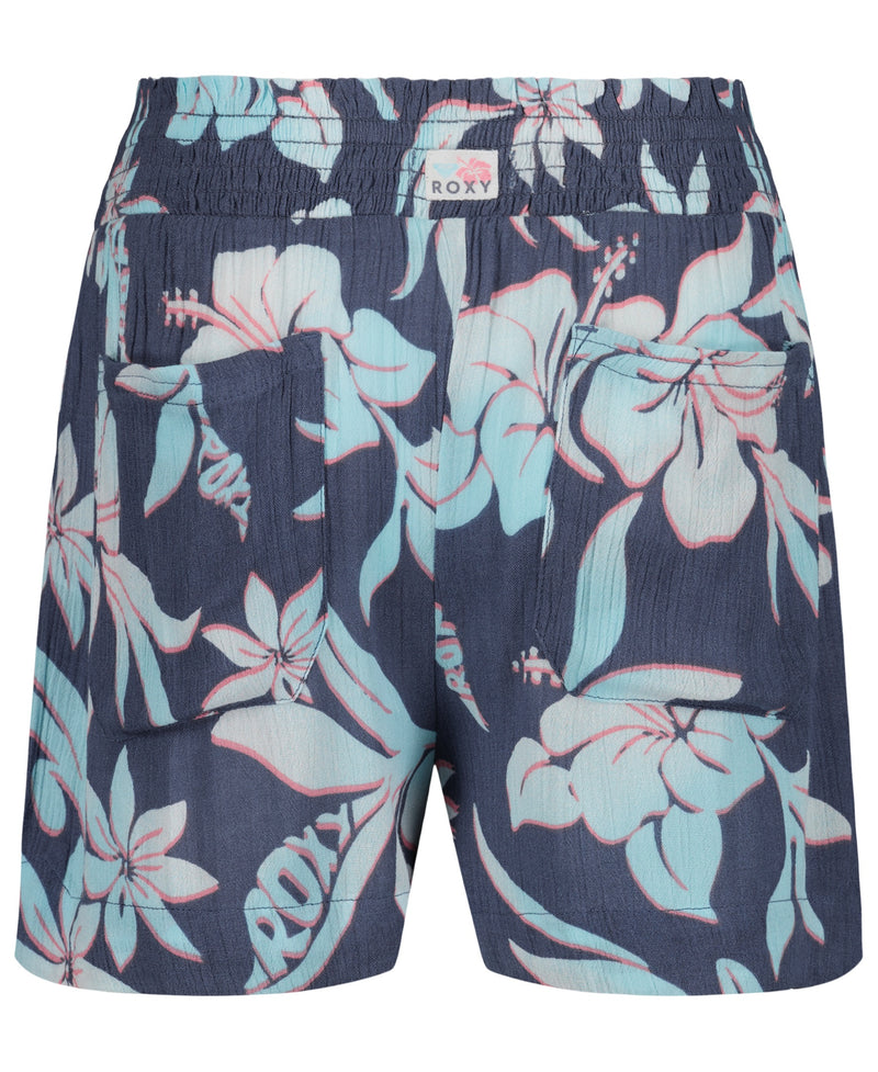 The Girls' Hula Soleil Short by Roxy features a navy blue base with pink and light blue hibiscus print, an elastic waistband, two back pockets, and a ROXY label—ideal beachwear for sunny days.