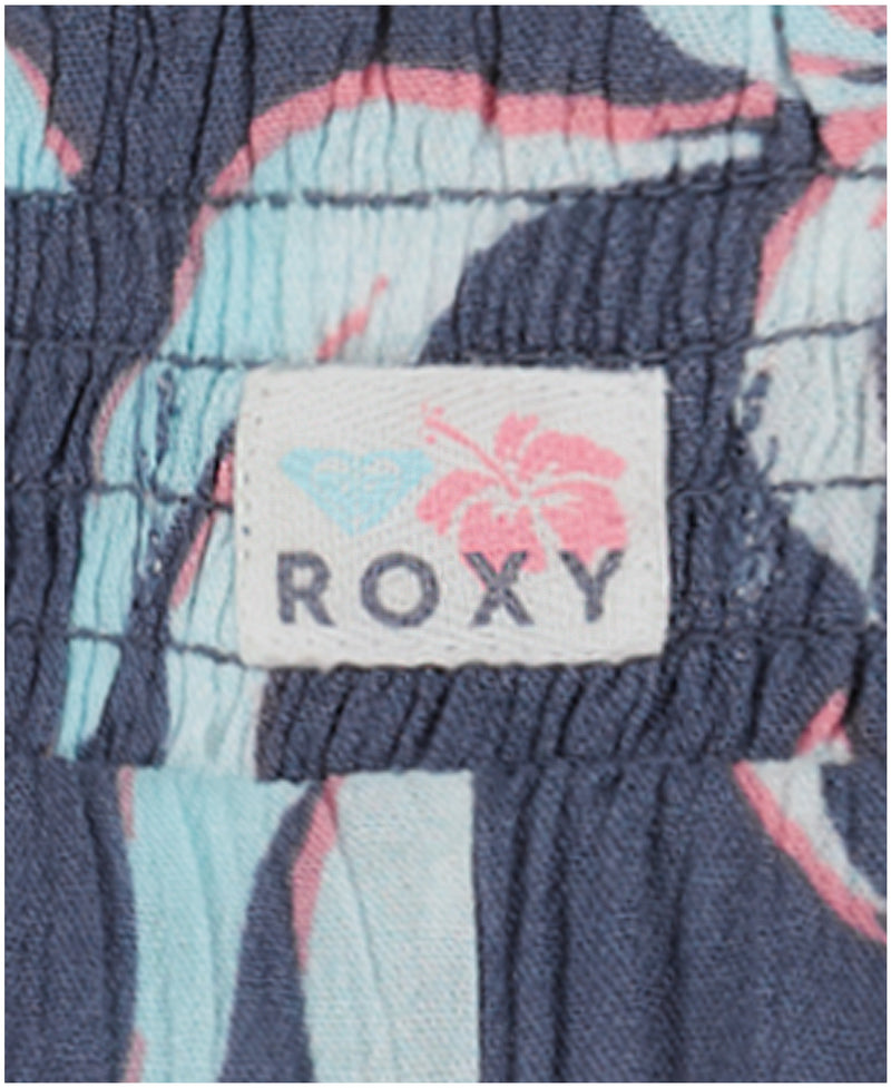 Close-up of a fabric label with the Roxy brand name and logo, sewn onto Girls' Hula Soleil Shorts in blue and pastel tropical print.