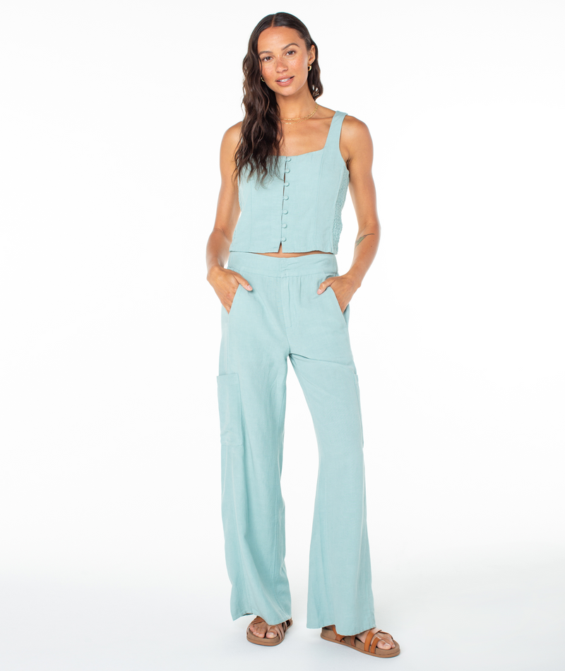 A woman wearing a Roxy Maui Sessions Top in light blue with a square-neck, button-front, and matching wide-leg trousers with side pockets.