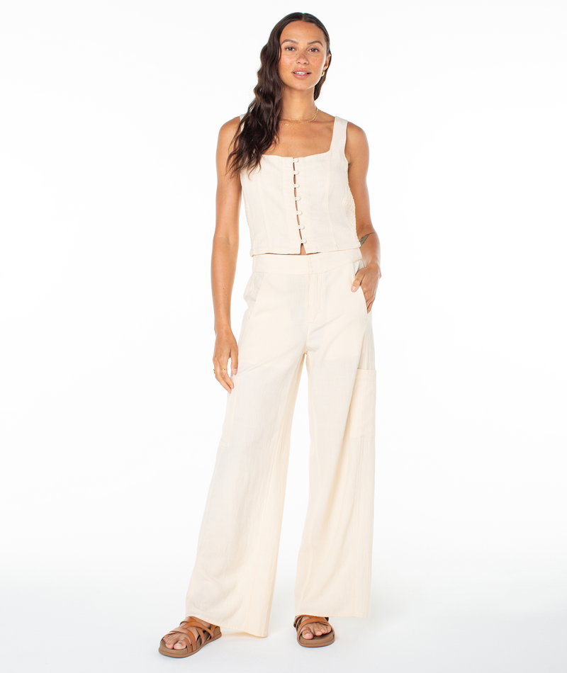 A woman wearing a cream-colored Roxy Maui Sessions Top and matching wide-leg trousers.