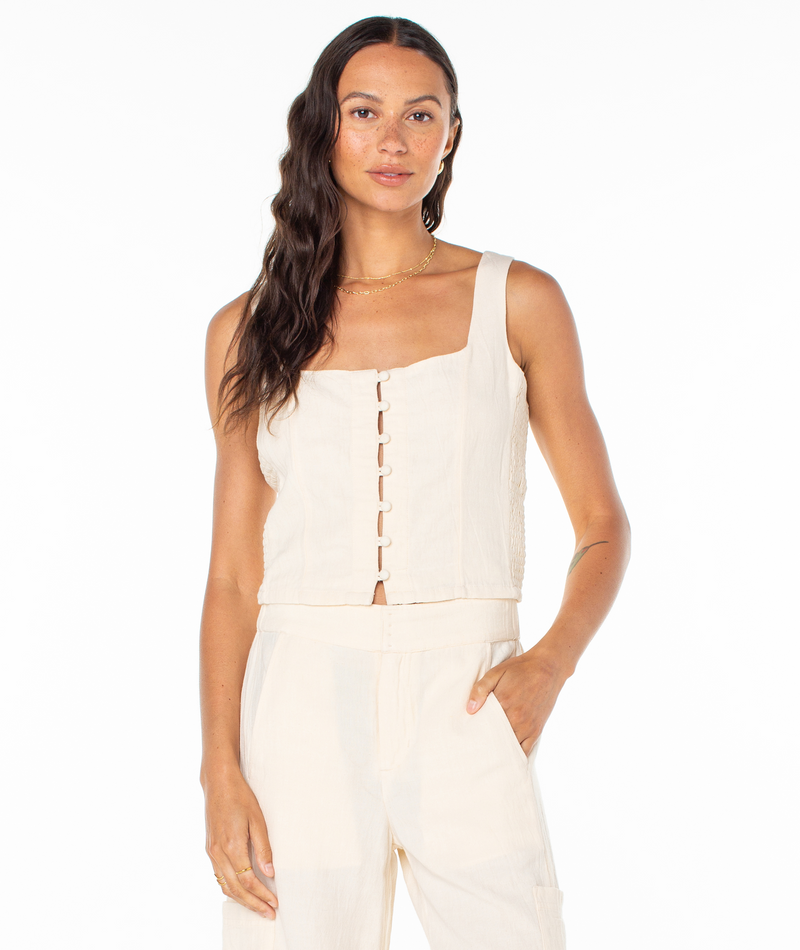 A woman wearing a sleeveless, cream-colored Roxy Maui Sessions Top with a square neckline and matching pants.