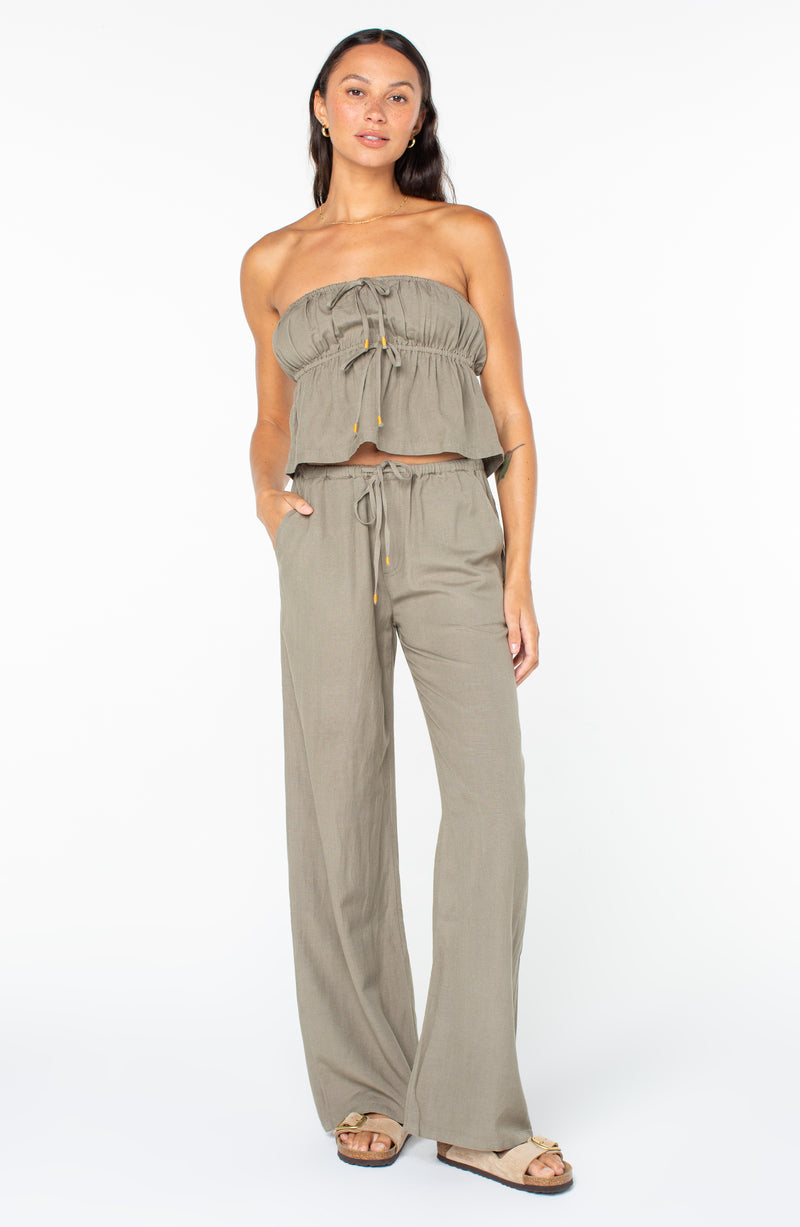 A person wearing a sage green Roxy Iyla Top with a tie-front detail and matching wide-leg drawstring pants.