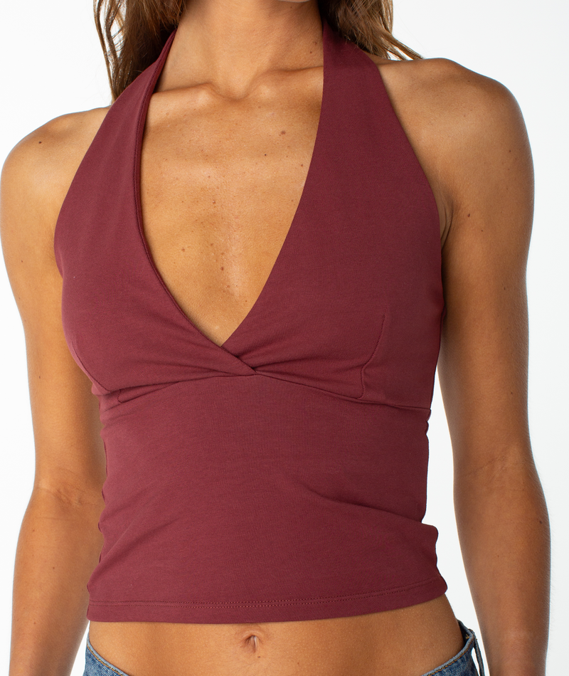 Model wears the Roxy South Shore Halter Tank—a sleeveless, deep V-neck maroon top with a fitted waist and cropped fit—shown from shoulders to waist against a white background.