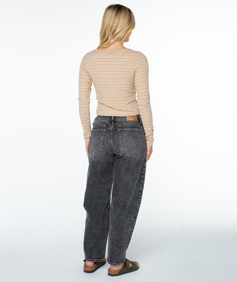 A person seen from behind wearing a tan, cropped V-neck Terrace Long Sleeve Knit Top, dark wash relaxed-fit jeans, and olive green sandals.