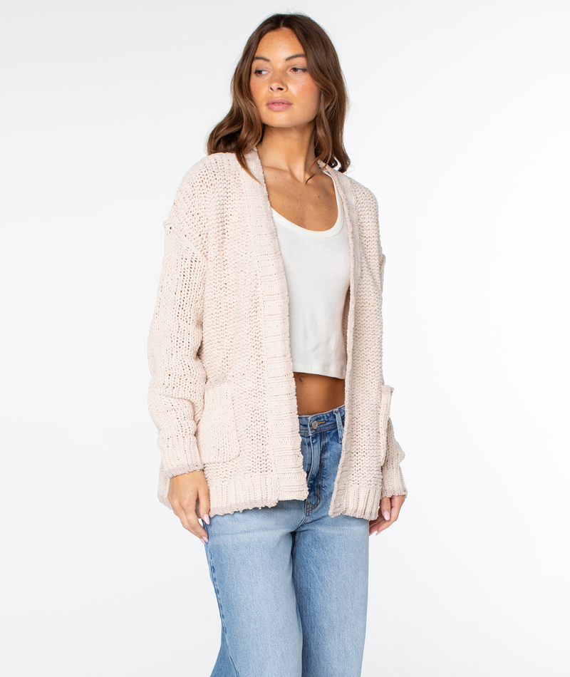 A person wearing a cozy cotton blend Roxy Cozy Cruiser Cardigan over a white tank top and blue jeans.