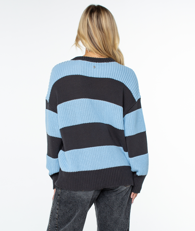 Back view of a person wearing a Roxy West Side Sweater, an oversized chunky knit crewneck with wide horizontal light blue and dark gray stripes.