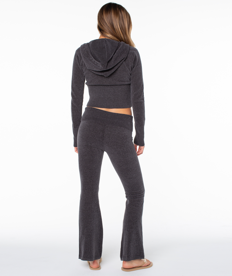 A person seen from behind wears a charcoal gray long-sleeve hooded top and matching Roxy Couch Surf Pant featuring a wide leg and a ribbed foldover waistband.