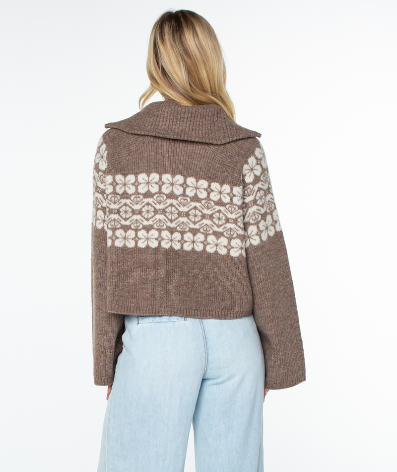 Back view of a relaxed-fit brown Cedar Grove Sweater by Roxy, featuring a wide collar and a repeating cream floral pattern across the chest and sleeves.
