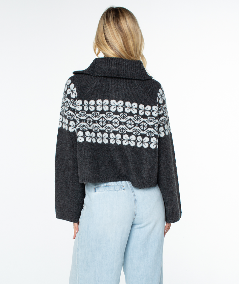 Back view of a dark gray Roxy Cedar Grove Sweater, a cropped quarter-zip with a white floral pattern across the chest and a wide collar, styled for a relaxed winter fit.