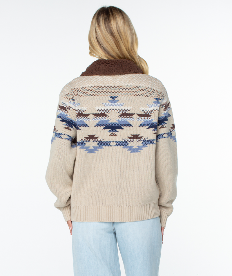 Back view of the Roxy Wildwood Sweater, a beige knit zip-up jacket with a brown collar and a blue, white, and brown geometric statement print across the chest and sleeves.