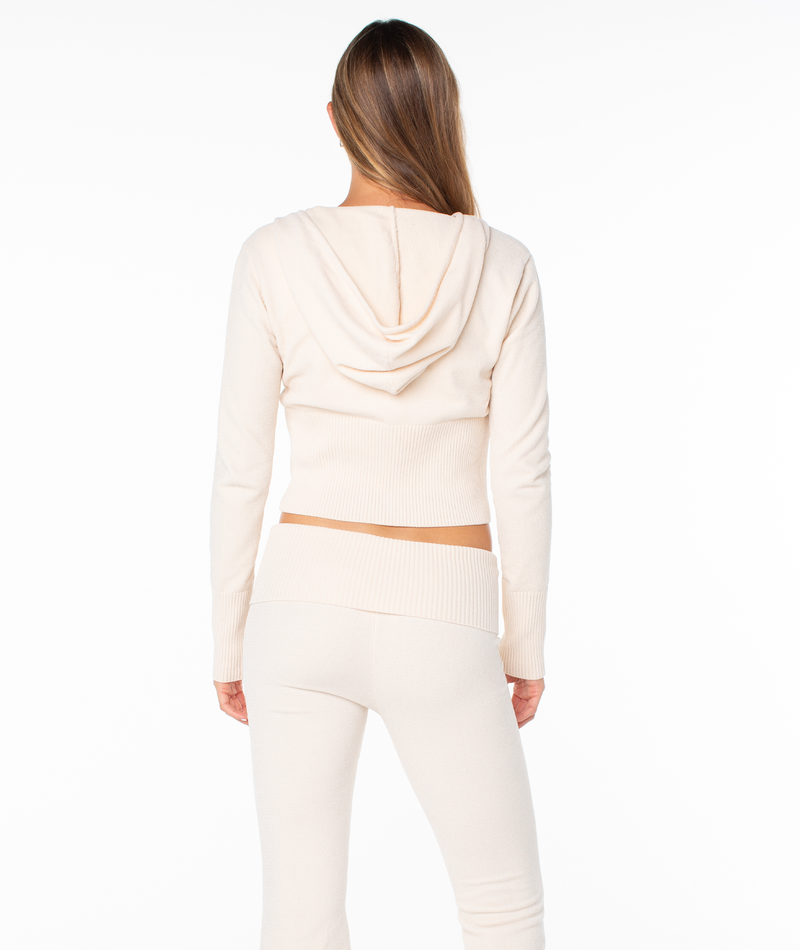 Back view of a person wearing a cozy, beige Roxy Double Daze 2 Top featuring a zip-up hooded crop design with a ribbed hem and matching pants for a comfortable fit.