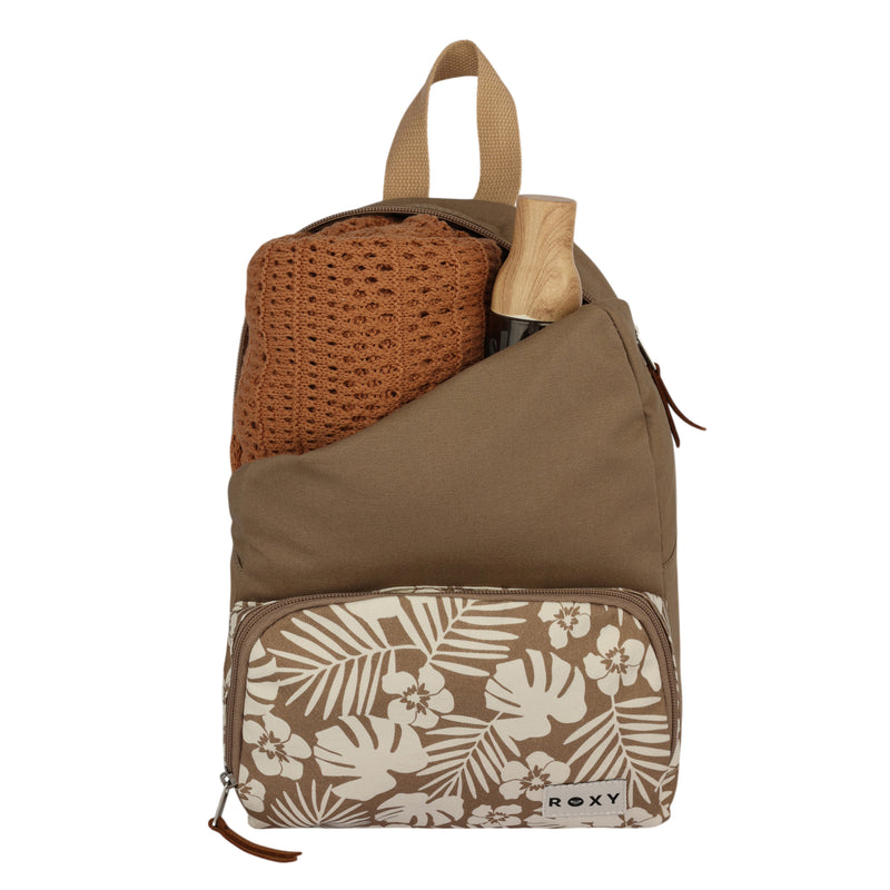 The Always Core Canvas Backpack by Roxy features a tan design with a floral front pocket, shown here containing a knit brown sweater and a partially visible wooden-handled item in the main compartment. It includes a loop handle on top and displays the Roxy logo.