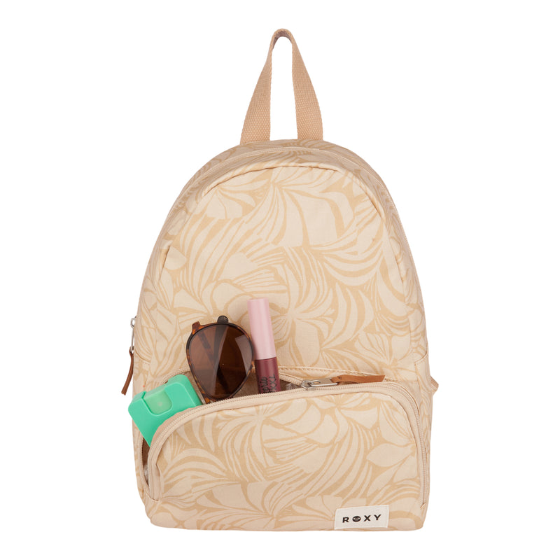 A beige, eco-conscious ROXY Always Core Canvas Backpack adorned with a subtle leaf pattern features a front pocket holding sunglasses, a green case, and a pink tube. This compact backpack includes a convenient top handle and prominently displays the ROXY label on the front.