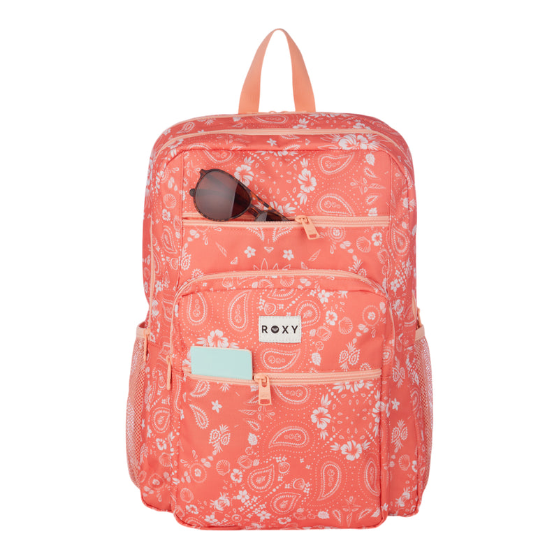 Roxy’s Campus Crush Backpack in coral pink features a paisley pattern on recycled polyester, a signature Roxy logo, a spacious front pocket holding a mint card, sunglasses neatly placed in the top zip pocket, breathable mesh side pockets, and well-designed organizer compartments—including a padded laptop sleeve for added protection.