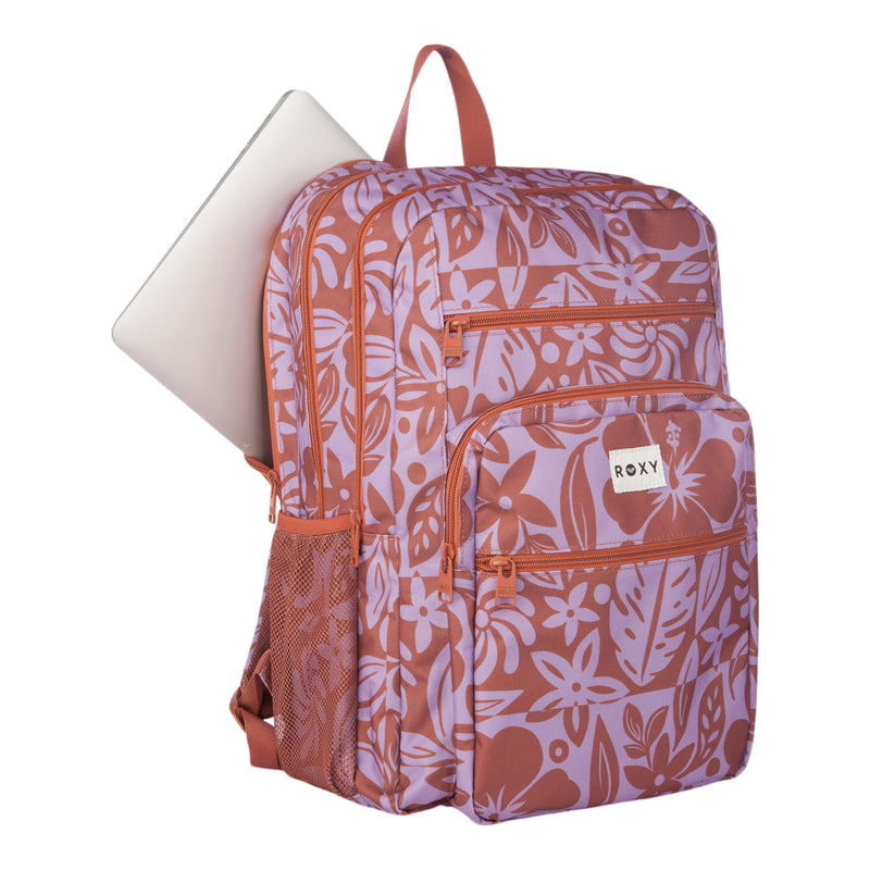 The Roxy Campus Crush Backpack is a pink and purple floral-patterned bag made from recycled polyester, featuring a padded laptop sleeve—with a laptop partially zipped into the main compartment—and a convenient mesh side pocket.