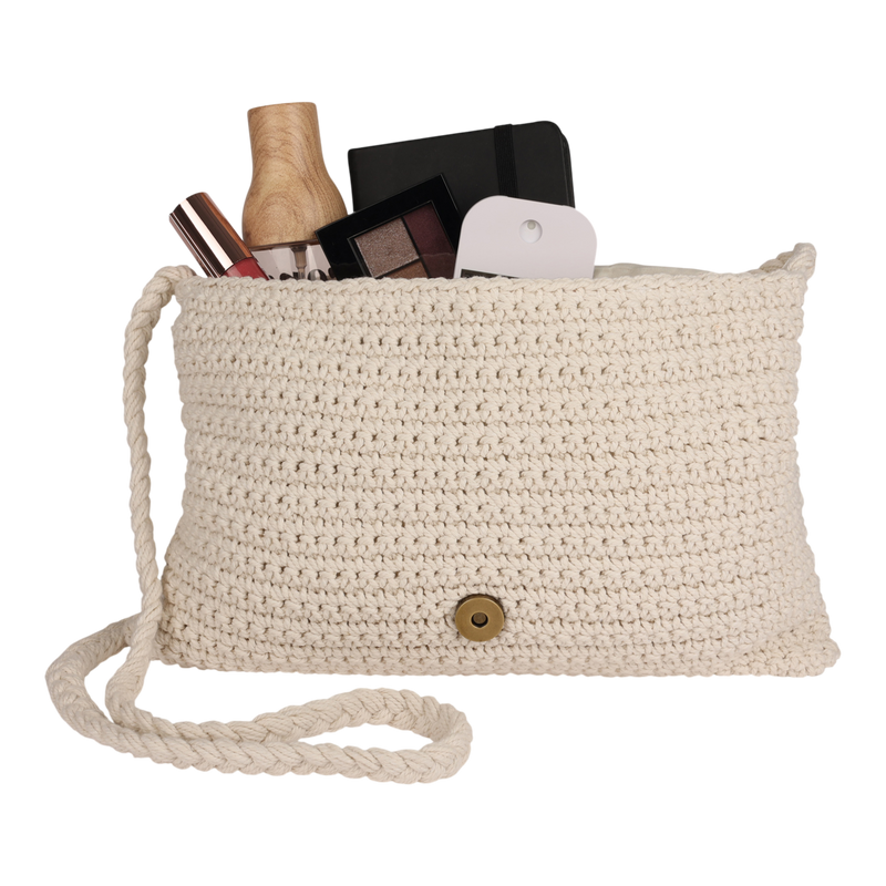 The Chips And Guac Medium Crossbody Bag by Roxy, in a cream crochet design with a button clasp, is shown filled with makeup items, a small notebook, a perfume bottle, and a white rectangular object against a white background—an everyday essential crafted for hands-free convenience.