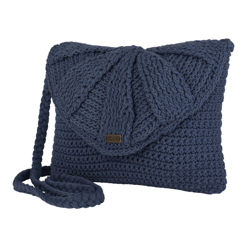Dark blue, hand-knitted shoulder bag with a textured flap design and a chunky braided strap. Designed as an everyday essential, this hands-free crossbody bag features a small rectangular metal tag on the front. The background is plain white.