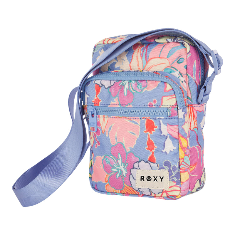 The ROXY Current Mood Crossbody Bag is a small bag with a vibrant floral pattern, featuring a front zipper pocket and a light purple adjustable strap. The “ROXY” label is displayed on the front.
