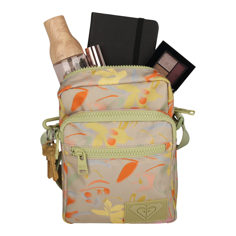 The Current Mood Crossbody Bag by Roxy is your ultimate adventure companion, featuring a compact floral design and an adjustable waist strap for versatile carrying. The main compartment offers a glimpse of essentials inside—a water bottle, notebook, three makeup products, and a partially visible eyeshadow palette.