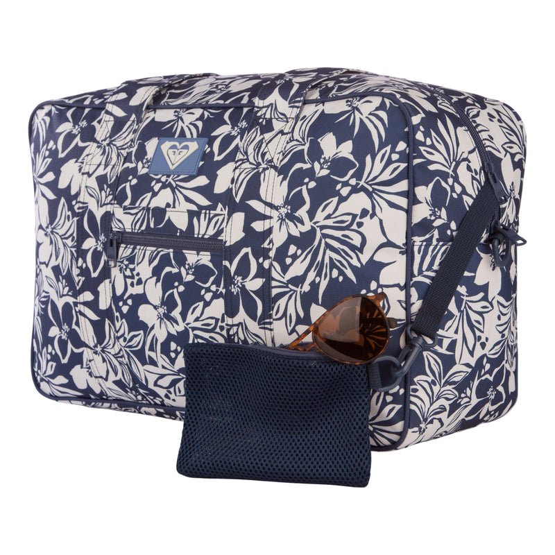 The Roxy Off Shore Duffel Bag, featuring a blue and white floral design, comes with a front pocket and a matching zippered pouch. Brown sunglasses are displayed in front of the pouch, all set against a white background. This stylish bag is an ideal choice for your next travel duffel.