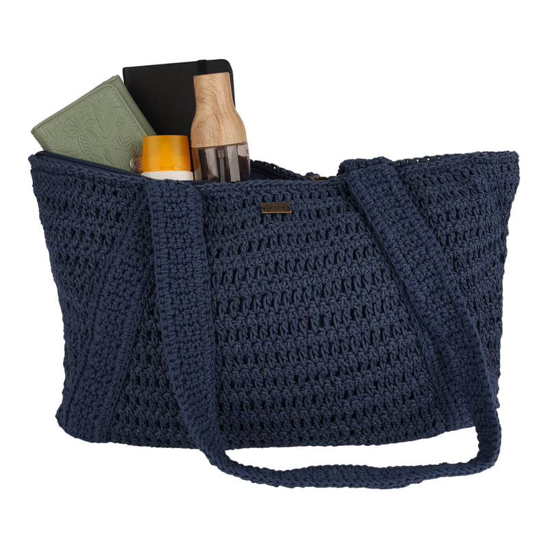 Introducing the Roxy Chips And Guac Tote Bag—a spacious navy blue crochet tote with two sturdy straps, designed to carry all your essentials. It comfortably holds a green notebook, a black book, a wooden water bottle, and a sunscreen bottle inside—making it the perfect travel companion for your everyday adventures.