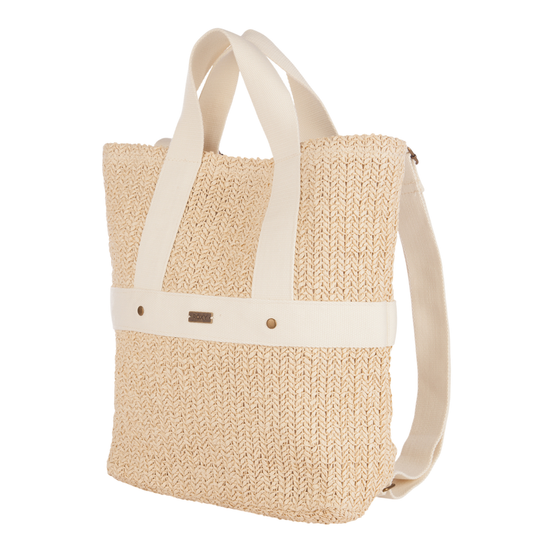 The Roxy Sunny Stash Backpack is a beige woven tote featuring sturdy cream fabric handles and a matching cream horizontal strap, accented by a small metal tag and two rivets on the front. Ideal for those seeking a chic alternative to the classic beach backpack, this stylish bag stands upright against a white background.