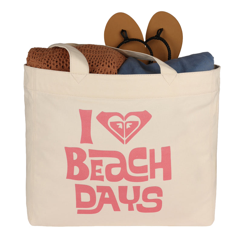 A ROXY Beach Days Tote Bag in beige recycled cotton, featuring "I love beach days" in pink letters, is filled with a brown towel, a blue item, and tan flip-flops.