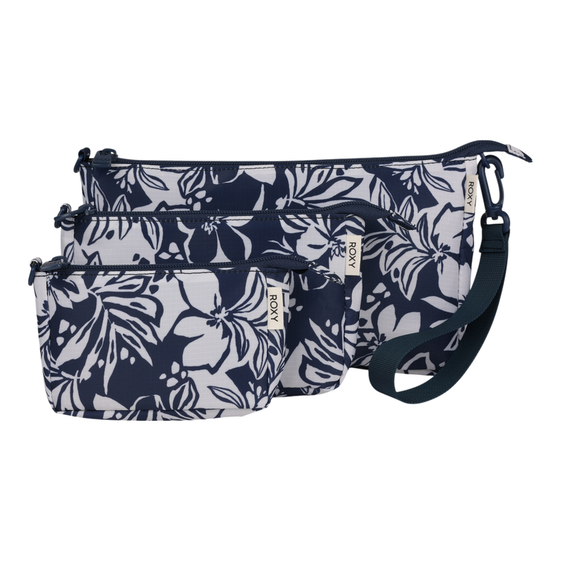 The Roxy Travel Pouch Set includes three zippered travel pouches in navy blue and white floral print, featuring varying sizes that stack together for easy packing organization, with the largest crossbody pouch equipped with a detachable wrist strap.