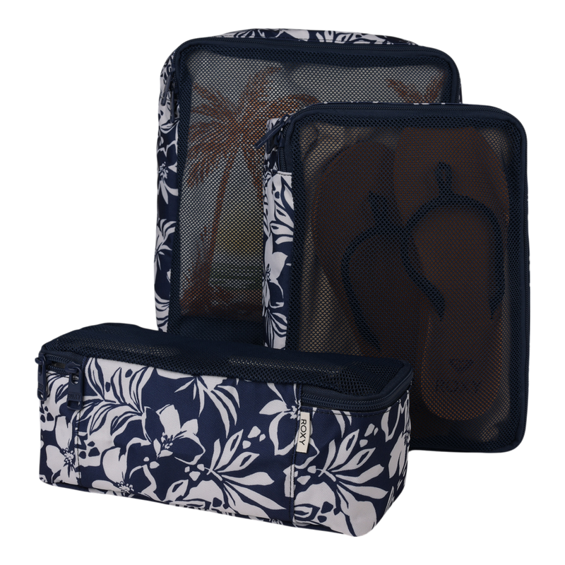 A set of three navy blue Roxy Packing Cubes adorned with white floral patterns and mesh fronts. Made from lightweight ripstop fabric, these travel essentials are perfect for organizing your luggage—one cube contains brown flip-flops, while another displays a palm tree print interior.