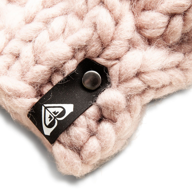Close-up of the chunky light pink knit fabric of the Roxy Winter Collar, perfect as a women’s scarf or chunky knit neck warmer for winter, featuring a black tag with a white heart-shaped logo and a metal rivet.
