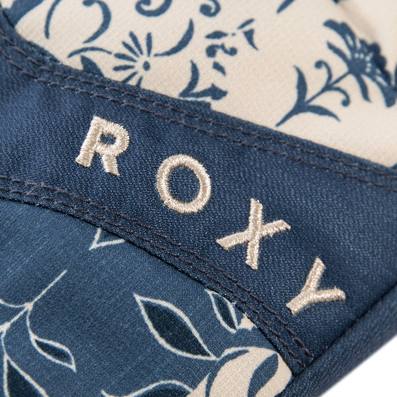 Close-up of blue denim fabric adorned with beige floral patterns and the embroidered word ROXY in cream-colored thread, reflecting the signature style of the Roxy Jetty Gloves by Roxy.