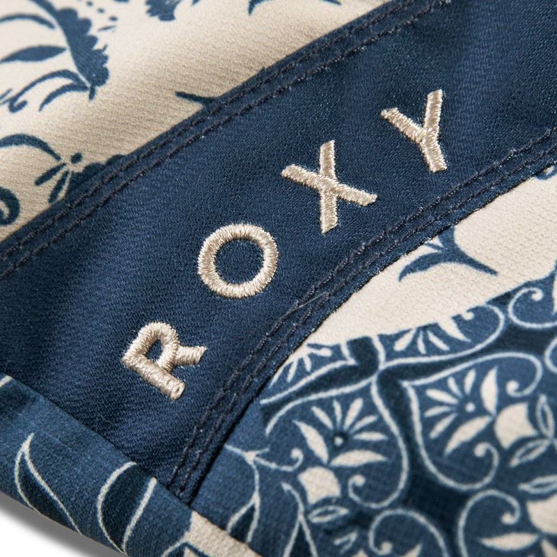 Close-up of the blue and white floral fabric on the Roxy Jetty Mitts by Roxy, with the brand’s name embroidered in white thread along a seam, highlighting the stylish detail on these waterproof mittens.