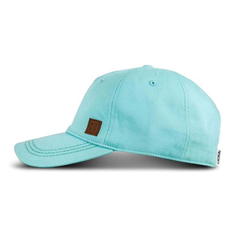 The Extra Innings Baseball Cap by Roxy is a light blue women’s cap crafted from soft cotton twill, featuring a curved visor, visible stitching, and a small brown patch with the Roxy logo on the side. The cap is displayed against a white background.