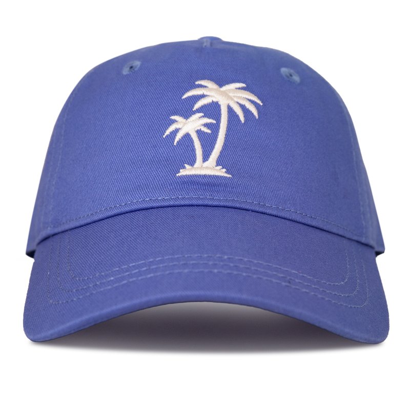 The Roxy Next Level Cap in Very Peri is a women’s baseball hat crafted from soft cotton twill, featuring two white embroidered palm trees on the front and a stylish curved visor, shown from the front against a white background.