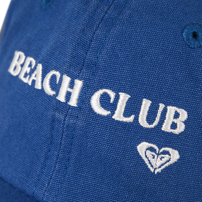 Close-up of the Toadstool Cap by Roxy—a blue fabric cap featuring white embroidered BEACH CLUB text above a small heart-shaped logo, offering the cool style that defines sleek baseball hats.