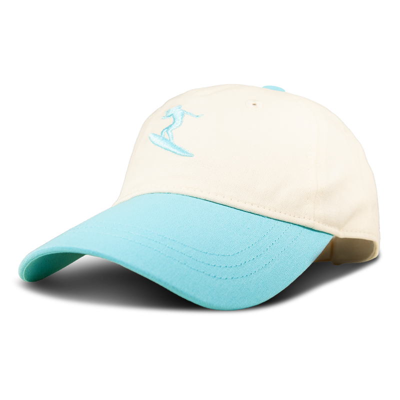 The Roxy Next Level Cap is a women’s baseball hat crafted from soft cotton twill, featuring a cream-colored crown and a light blue curved visor, accented with an embroidered surfer on the front.