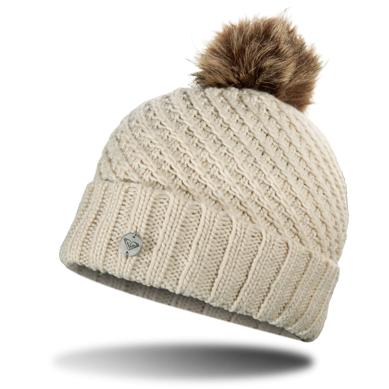 Cream-colored Roxy Blizzard Beanie in a chunky knit with a ribbed cuff, a small metallic logo charm, and a faux fur pom-pom on top.
