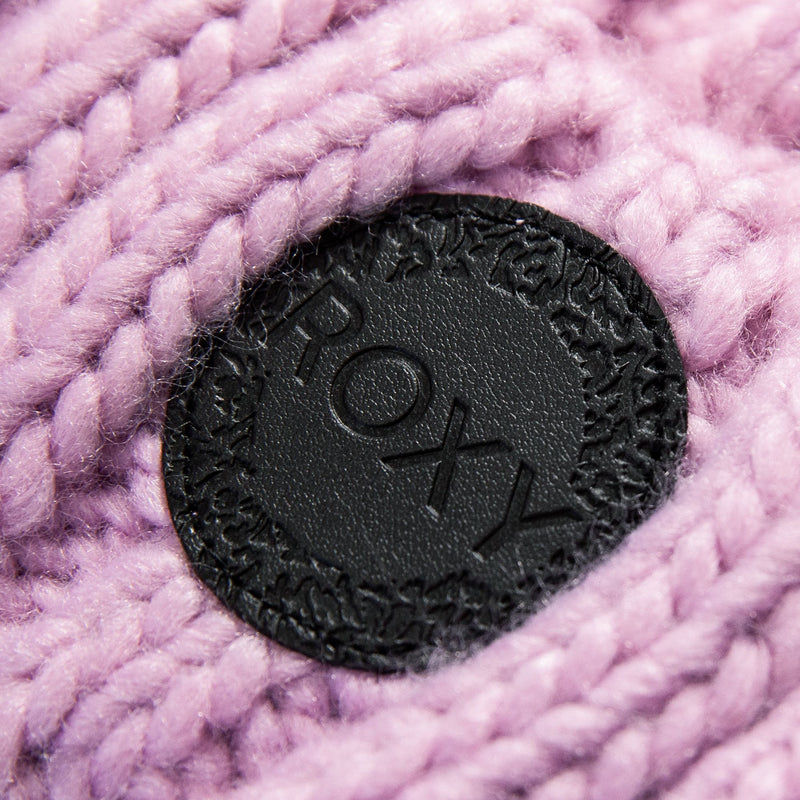 Close-up of a black leather patch embossed with the ROXY logo, attached to the knitted pink fabric of the Tram Beanie—a stylish accessory from Roxy that’s perfect for adding flair to your favorite cable knit beanie.