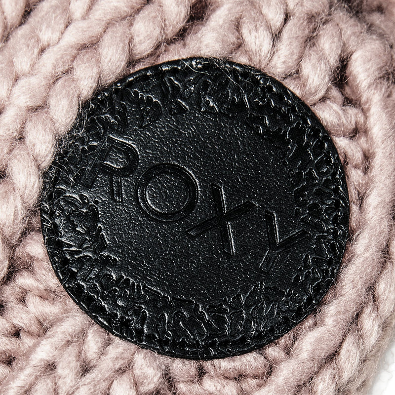 A close-up of a black leather patch with the ROXY logo embossed on it, sewn onto the knitted pink fabric of the Tram Beanie, highlights the stylish detailing of this women’s accessory from Roxy.