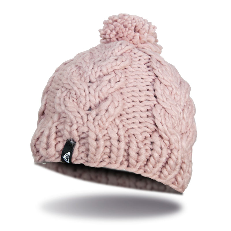 The Roxy Winter Beanie is a chunky knit, light pink hat featuring a pom-pom on top and a small black tag, shown against a white background with a subtle shadow beneath it.