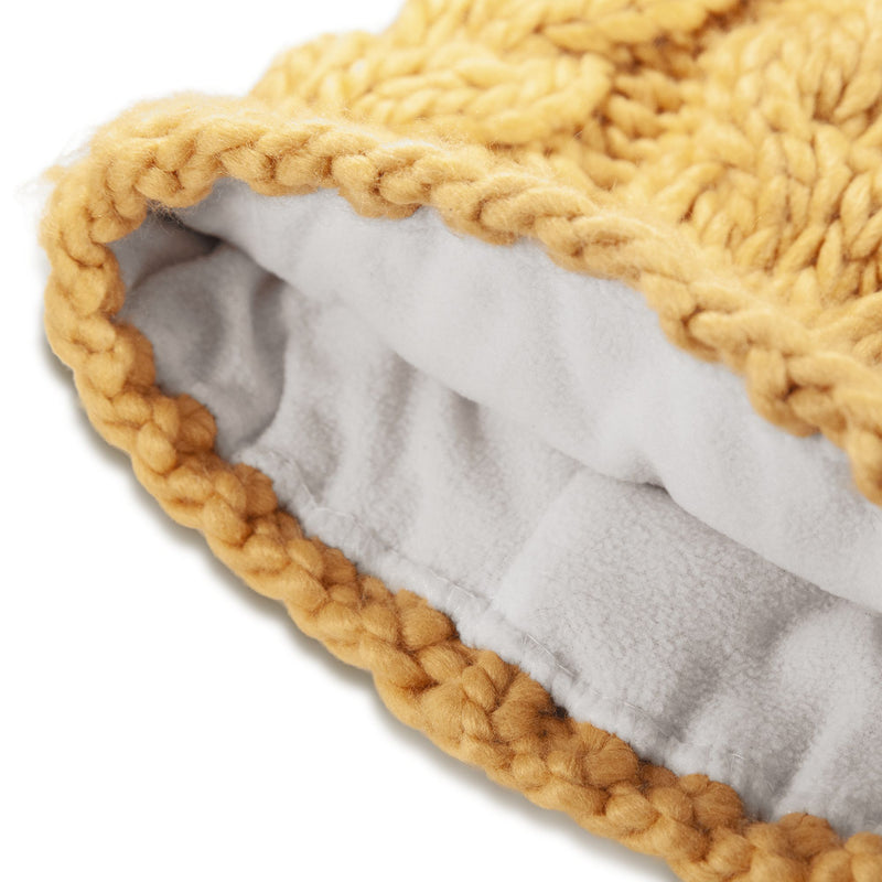 Close-up of the Roxy Winter Beanie, showcasing its thick, chunky yellow knit yarn and soft white fleece lining. The focus is on the beanie’s edge, highlighting the texture and warmth of this cozy women’s winter accessory.