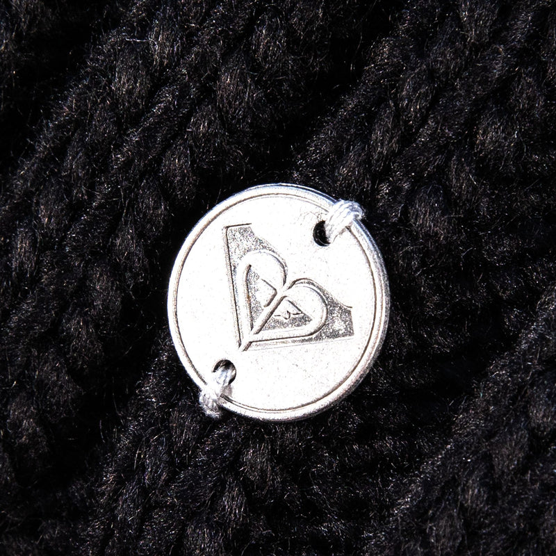 A round silver button engraved with a heart-shaped Roxy logo is attached to the Roxy Girls Blizzard Girl Beanie—a textured black cable knit hat—by two pieces of gray thread.