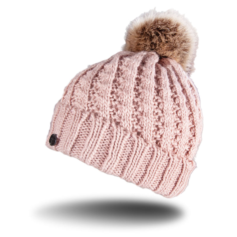 The Roxy Girls Blizzard Girl Beanie by Roxy is a pink cable knit hat topped with a large brown faux fur pom-pom, featuring a cozy polar fleece lining, and is shown against a white background with a shadow beneath it.